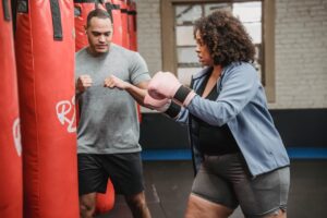 Ethnic trainer showing hit bag to plus size blag female